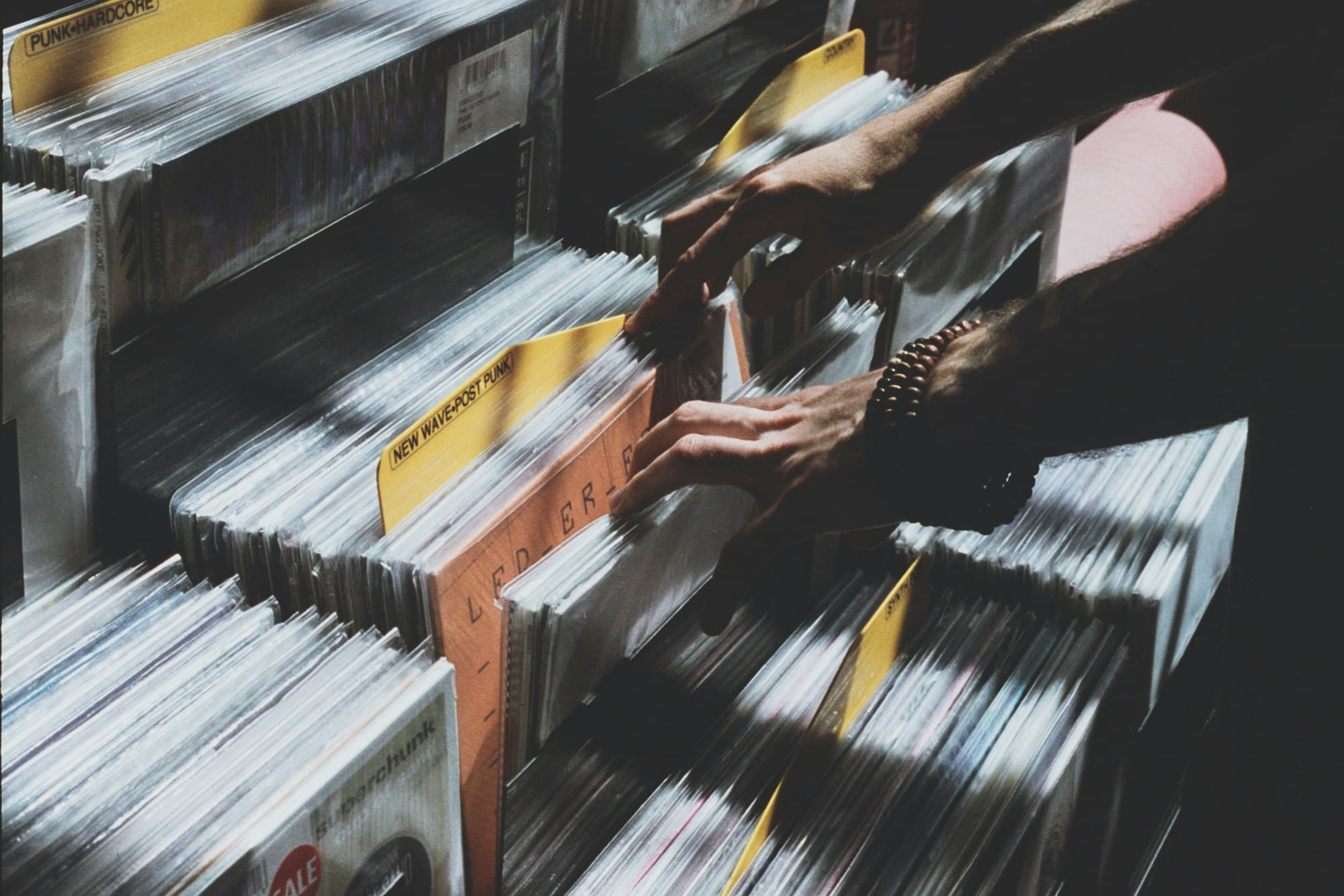 Hands flipping through crates of vinyl records in a record store